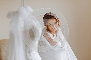 The morning of the bride in a white robe and an elegant hairstyle