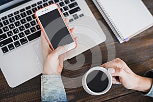 Morning business woman. Laptop on the desk, phone and a cup of coffee in female hands. Horizontal frame