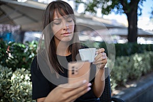 Morning in cafe - attractive woman in black drinkin coffe and make selfie photo for social networks