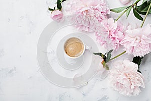 Morning coffee and beautiful pink peony flowers on white stone table top view in flat lay style. Cozy breakfast on Mother day.