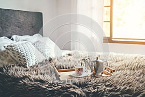 Morning `coffee in bed` still life. Cozy bedroom shot with coffee pot and cup on the fir bed blanket with magic background window