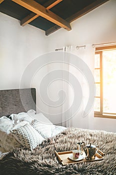Morning `coffee in bed` vertical still life. Cozy bedroom shot with coffee pot and cup on the fir bed blanket with magic backgroun