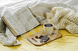 Morning Coffee With Bible Illuminated By Sunlight. Cup of coffee with Christian Bible. White bedroom. Chocolate and coffee cup.