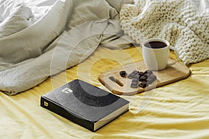 Morning Coffee With Bible Illuminated By Sunlight. Cup of coffee with Christian Bible. White bedroom. Chocolate and coffee cup.