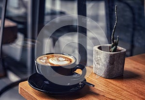 Morning coffee in a black cup on wooden table