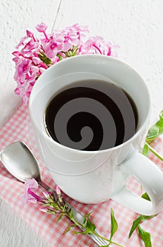 Morning coffee or cup of tea with pink flowers.