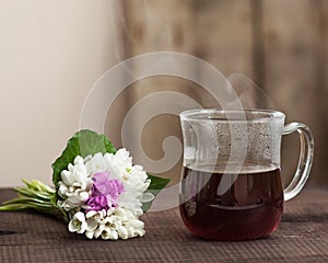 Morning coffee in glass cup with fresh spring flowers bouqet on wood background