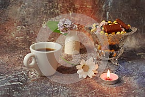 Morning coffee in a hurry: a cup of coffee, flowers in a vase, dried fruits and sweets in a vase, a burning candle