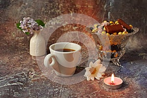 Morning coffee in a hurry: a cup of coffee, flowers in a vase, dried fruits and sweets in a vase, a burning candle