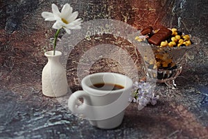 Morning coffee in a hurry: a cup of coffee, flowers in a vase, dried fruits and sweets in a vase, a burning candle