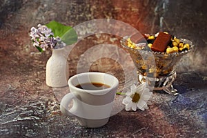 Morning coffee in a hurry: a cup of coffee, flowers in a vase, dried fruits and sweets in a vase, a burning candle
