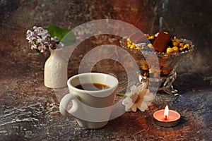 Morning coffee in a hurry: a cup of coffee, flowers in a vase, dried fruits and sweets in a vase, a burning candle
