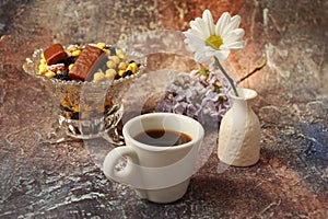 Morning coffee in a hurry: a cup of coffee, flowers in a vase, dried fruits and sweets in a vase, a burning candle