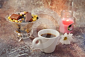 Morning coffee in a hurry: a cup of coffee, flowers in a vase, dried fruits and sweets in a vase, a burning candle