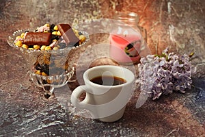 Morning coffee in a hurry: a cup of coffee, flowers in a vase, dried fruits and sweets in a vase, a burning candle