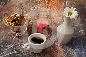 Morning coffee in a hurry: a cup of coffee, flowers in a vase, dried fruits and sweets in a vase, a burning candle