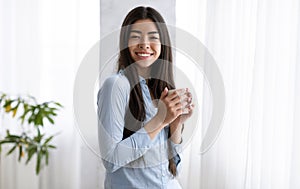 Morning Coffee. Smiling Korean Woman Enjoying Hot Drink Near Window At Home