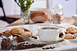 Morning coffee in white cup, chocolate chips cookies on cutting board close-up, selective focus