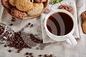 Morning coffee in white cup, chocolate chips cookies on cutting board close-up, selective focus