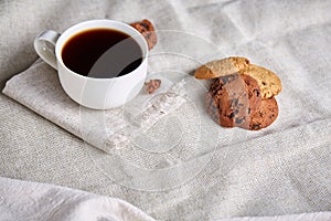 Morning coffee in white cup, chocolate chips cookies on cutting board close-up, selective focus