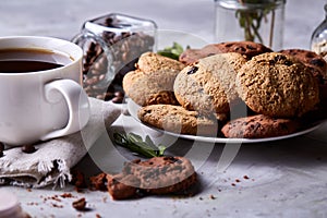 Morning coffee in white cup, chocolate chips cookies on homespun napkin, close-up, selective focus