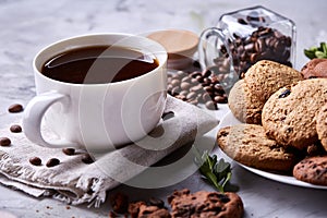 Morning coffee in white cup, chocolate chips cookies on homespun napkin, close-up, selective focus