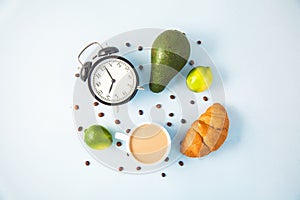 Morning coffee in a white cup Croissant Avocado Awakening with an alarm clock Breakfast cheerfulness, a healthy breakfast freshnes