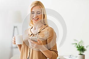 Morning coffee. Woman responding emails on smartphone