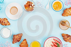 Morning continental breakfast with coffee, croissant, oatmeal, jam, honey and juice on blue table top view. Flat lay.