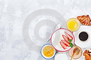 Morning continental breakfast with coffee, croissant, oatmeal, jam, honey and juice on stone table from above. Flat lay.