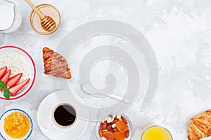 Morning continental breakfast with coffee, croissant, oatmeal, jam, honey and juice on stone table top view. Flat lay style.