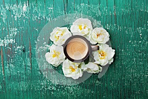 Morning cup of coffee and beautiful roses flowers on teal rustic table top view. Cozy Breakfast. Flat lay style.