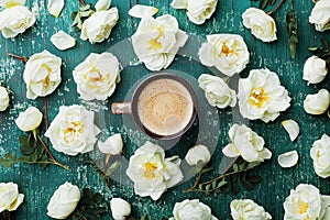 Morning cup of coffee and beautiful roses flowers on teal vintage background top view. Cozy Breakfast. Flat lay style.