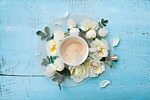Morning cup of coffee and beautiful roses flowers on turquoise rustic table top view. Cozy Breakfast. Flat lay style.