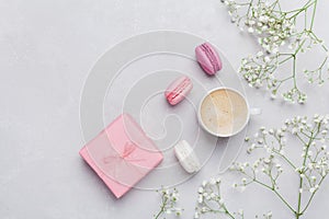 Morning cup of coffee, cake macaron, gift or present box and flower on light table from above. Beautiful breakfast. Flat lay.