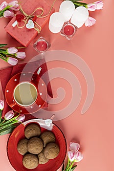 Morning cup of coffee, chocolate cake, gift or present box, candles and flower on pink table from above. Romantic Valentines Day