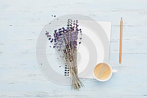 Morning cup of coffee, clean notebook and lavender flower on blue background top view. Woman working desk. Cozy breakfast.Flat lay