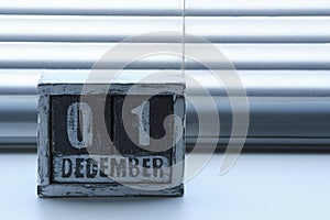 Morning December 01 on wooden calendar standing on window with blinds.