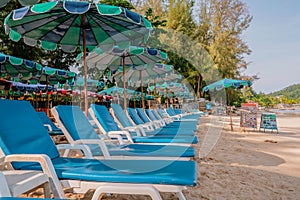 Morning empty tropical sunny beach with plastic chairs under umbrellas. Happy tropical vacations concept