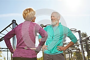 Morning exercises. Happy senior family couple in sportswear doing gymnastics together at outdoor gym. Man and woman