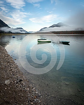 Morning fog and boats in autumn at Sylvenstein reservoir in Bavaria