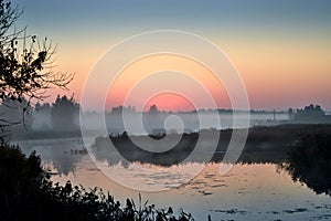 Morning fog on the lake, sunrise shot. Summer or autumn landscape.