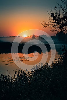 Morning fog on the lake, sunrise shot. Summer or autumn landscape. Vertical view.