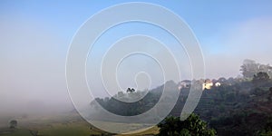 Morning fog over rice fields, sun shines through to small clay buildings - typical landscape in Alakamisy region of