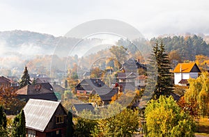 Morning with fog and smoke over the houses in the village in autumn