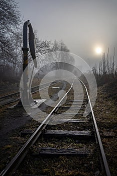 Morning foggy landscape with railway tracks and historic water crane, which was used in past to add water to steam locomotives