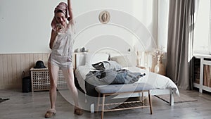 Morning fun background of sofa cushions funny girl dressed in nightwear home slippers, wearing wireless headphones