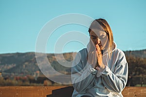 In the morning Girl closed her eyes, praying outdoors, Hands folded in prayer concept for faith, spirituality, religion concept.