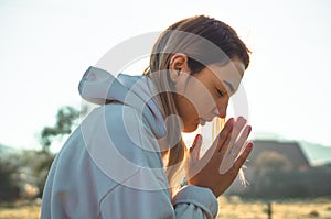 In the morning Girl closed her eyes, praying outdoors, Hands folded in prayer concept for faith, spirituality, religion concept.