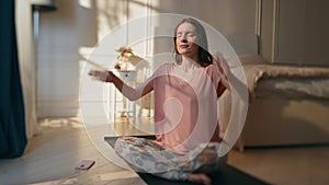 Morning girl doing yoga in sunlight home. Calm relaxed woman in lotus position